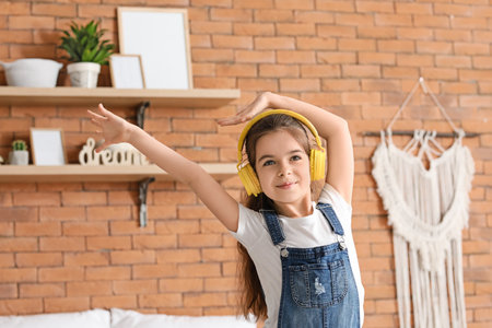 Cute little girl listening to music at homeの写真素材