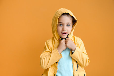 Cute little girl in raincoat on color backgroundの写真素材
