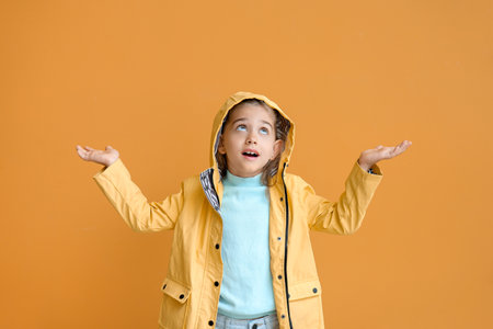 Cute little girl in raincoat on color backgroundの写真素材