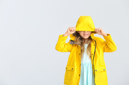Cute little girl in raincoat on gray backgroundの写真素材