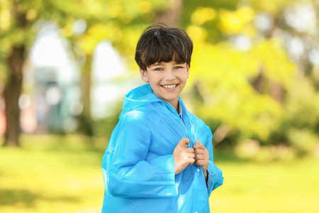 Cute little boy wearing raincoat in park