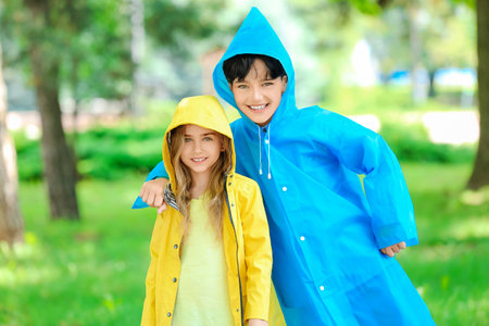 Cute little children wearing raincoats in parkの写真素材