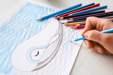 Woman coloring picture at table, closeupの写真素材