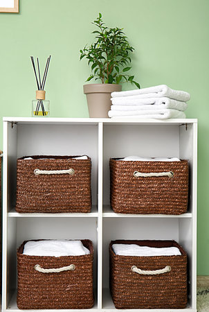 Rack with wicker baskets and towels in the roomの写真素材