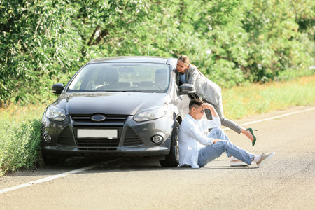 Young couple near broken car on roadの写真素材