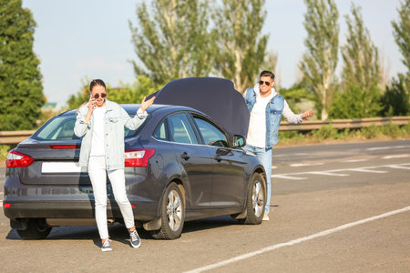 Young couple near broken car on roadの写真素材