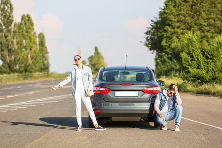 Young couple near broken car on roadの写真素材