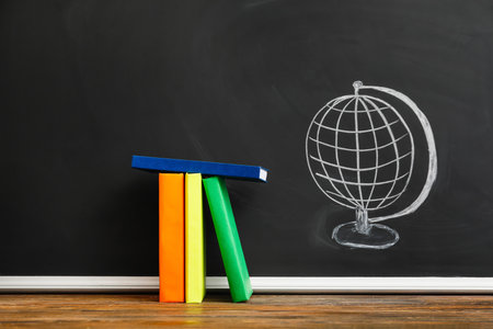 Books on table against school blackboardの写真素材