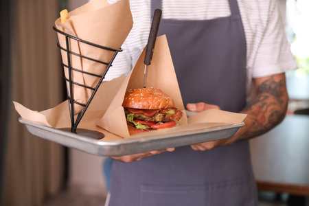 Young male waiter with dish in restaurant, closeupの写真素材