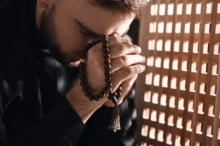 Young priest in confession boothの写真素材