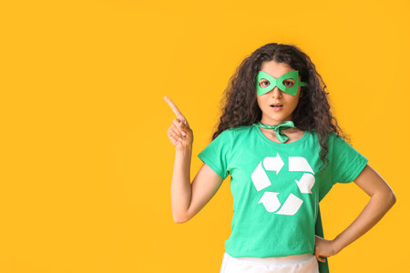 Woman dressed as eco superhero showing something on color backgroundの写真素材