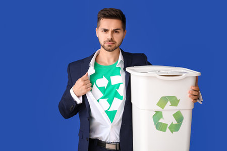Man in t-shirt with recycling sign and trash bin on color background. Ecology conceptの写真素材