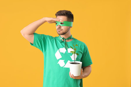 Man dressed as eco superhero with plant on color backgroundの写真素材