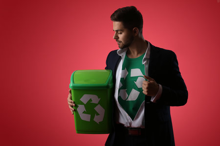 Man in t-shirt with recycling sign and trash bin on color background. Ecology conceptの写真素材