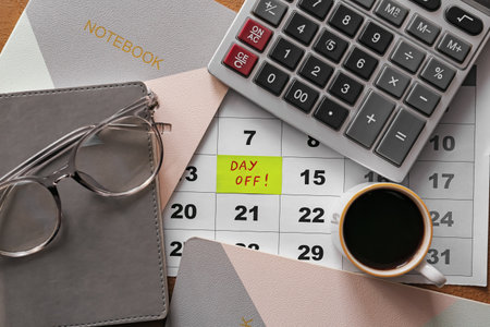 Stationery with cup of coffee and calendar with text DAY OFF at workplaceの写真素材