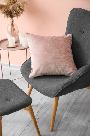 Stylish armchair with pillow near color wall in roomの写真素材