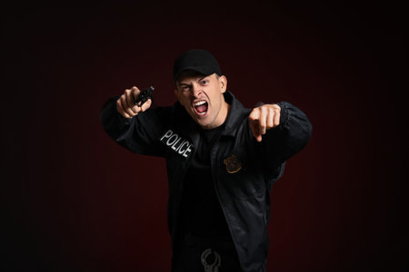 Aggressive police officer with gun on dark backgroundの写真素材