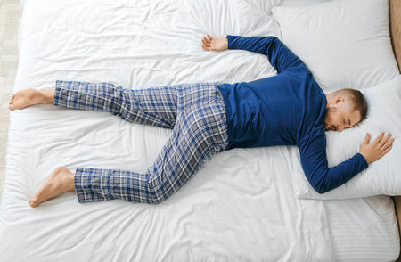 Young man sleeping in bed at homeの写真素材