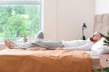 Young man sleeping in bed at homeの写真素材