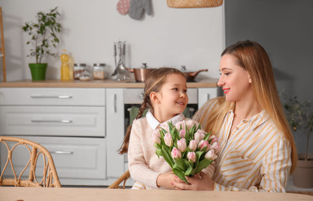 Cute little girl with her mother and tulips in the kitchen