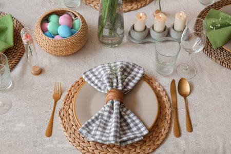 Beautiful Easter table setting with eggs and candles in dining room, closeup