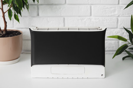 Air purifier and houseplants on table near white brick wallの写真素材