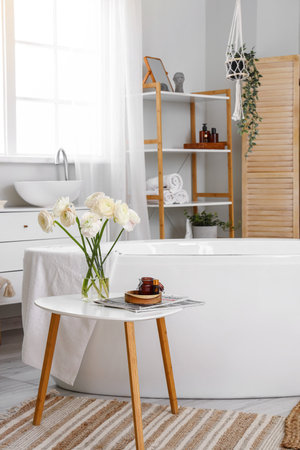 Interior of bathroom with ranunculus flowers in vase on table