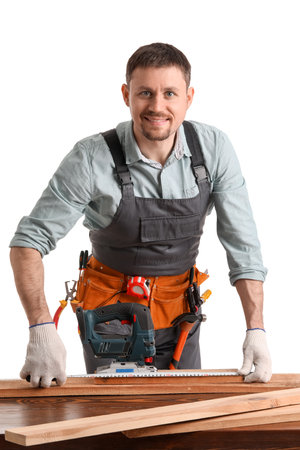 Male carpenter measuring wooden plank at table on white backgroundの写真素材