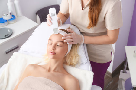 Woman undergoing procedure of facial peeling in beauty salonの写真素材