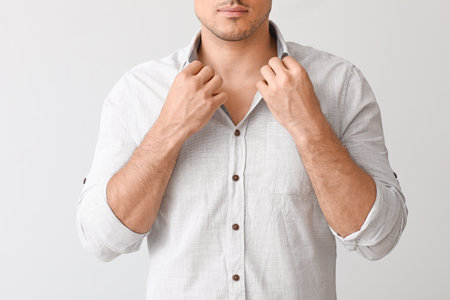 Young businessman in stylish shirt on light backgroundの写真素材