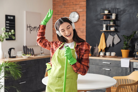 Young woman having fun while cleaning kitchenの写真素材