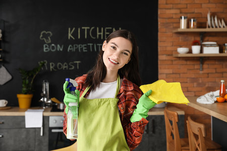Beautiful young woman cleaning kitchenの写真素材