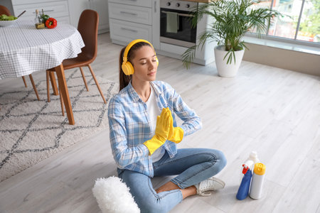 Beautiful young woman meditating during cleaning of kitchenの写真素材