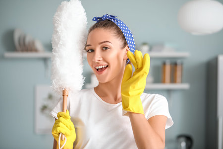 Beautiful young woman cleaning kitchen