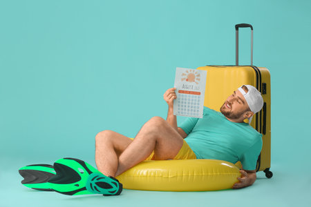 Young man with calendar and suitcase on color background. vacation conceptの写真素材