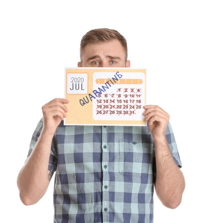 Sad man holding calendar with written word QUARANTINE against white backgroundの写真素材