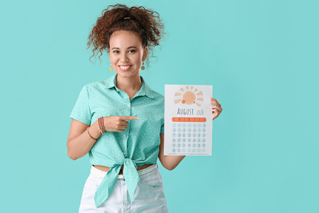 Young woman with calendar on color background. vacation conceptの写真素材