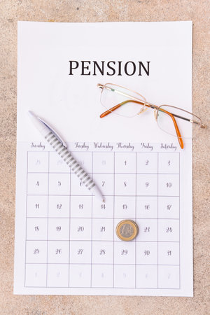 Calendar with coins, eyeglasses and pen on gray background. concept of retirementの写真素材