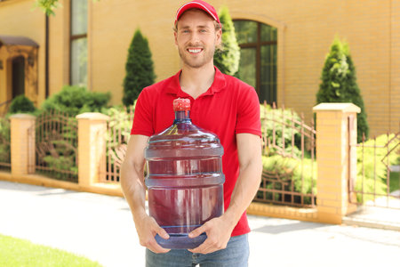 Delivery man with bottle of water outdoorsの写真素材