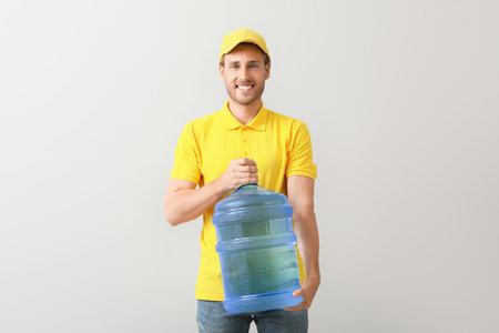 Delivery man with bottle of water on gray backgroundの写真素材