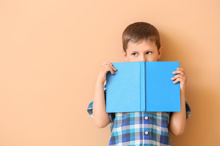 Cute little boy with book on color backgroundの写真素材