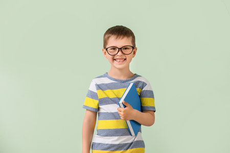 Cute little boy with book on color backgroundの写真素材
