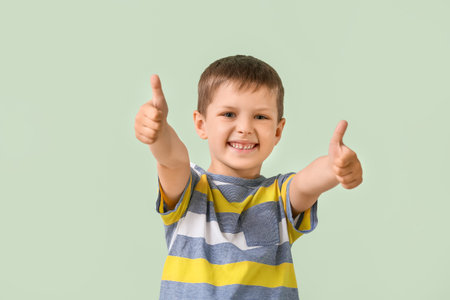 Cute little boy showing thumb-up on color backgroundの写真素材