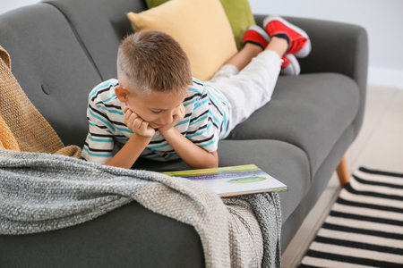 Cute little boy reading book at homeの写真素材