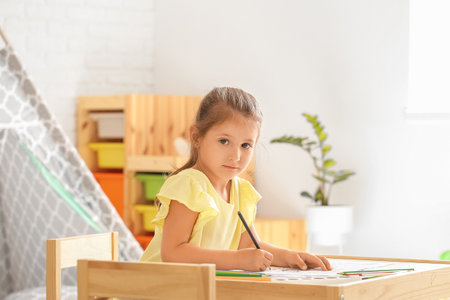 Cute little girl coloring pictures at homeの写真素材