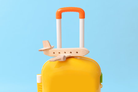 Packed kid suitcase with wooden airplane on color backgroundの写真素材