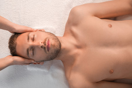 Handsome young man receiving massage in spa salonの写真素材