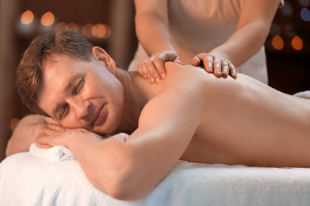 Handsome man receiving massage in spa salonの写真素材