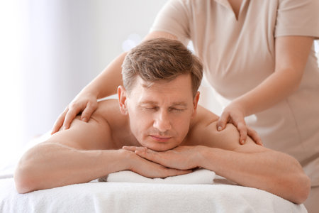 Handsome man receiving massage in spa salonの写真素材