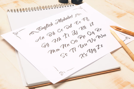 Notebook and paper sheet with alphabet on tableの写真素材